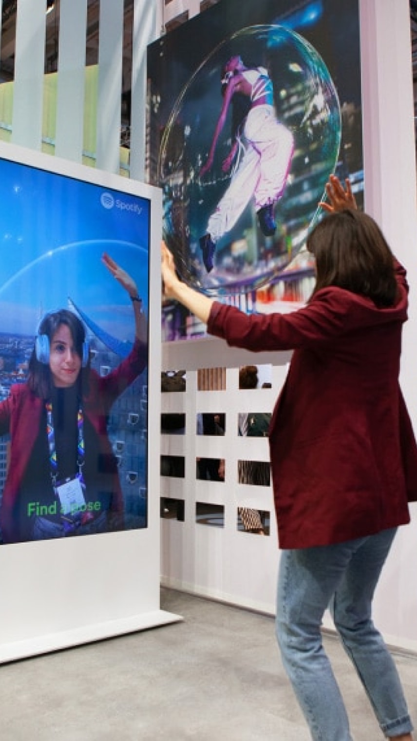 A person interacts with a digital display featuring an animated bubble and vibrant visuals, while wearing headphones.